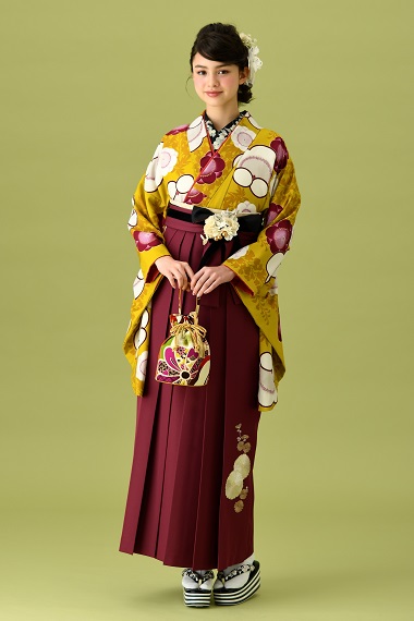 山本寛斎ブランドの、からし地にワインレッドの花柄の二尺袖と、ワインレッドの袴の女性用卒業式袴を着用した全身写真