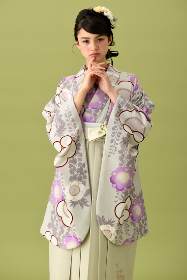 山本寛斎ブランドの、白地に紫の花柄の二尺袖と、白の袴の女性用卒業式袴を着用したアップ写真