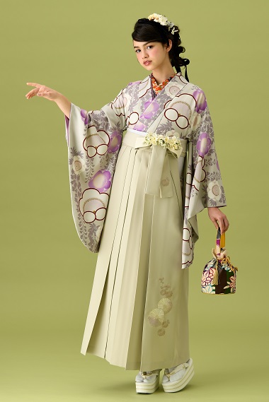 山本寛斎ブランドの、白地に紫の花柄の二尺袖と、白の袴の女性用卒業式袴を着用した全身写真