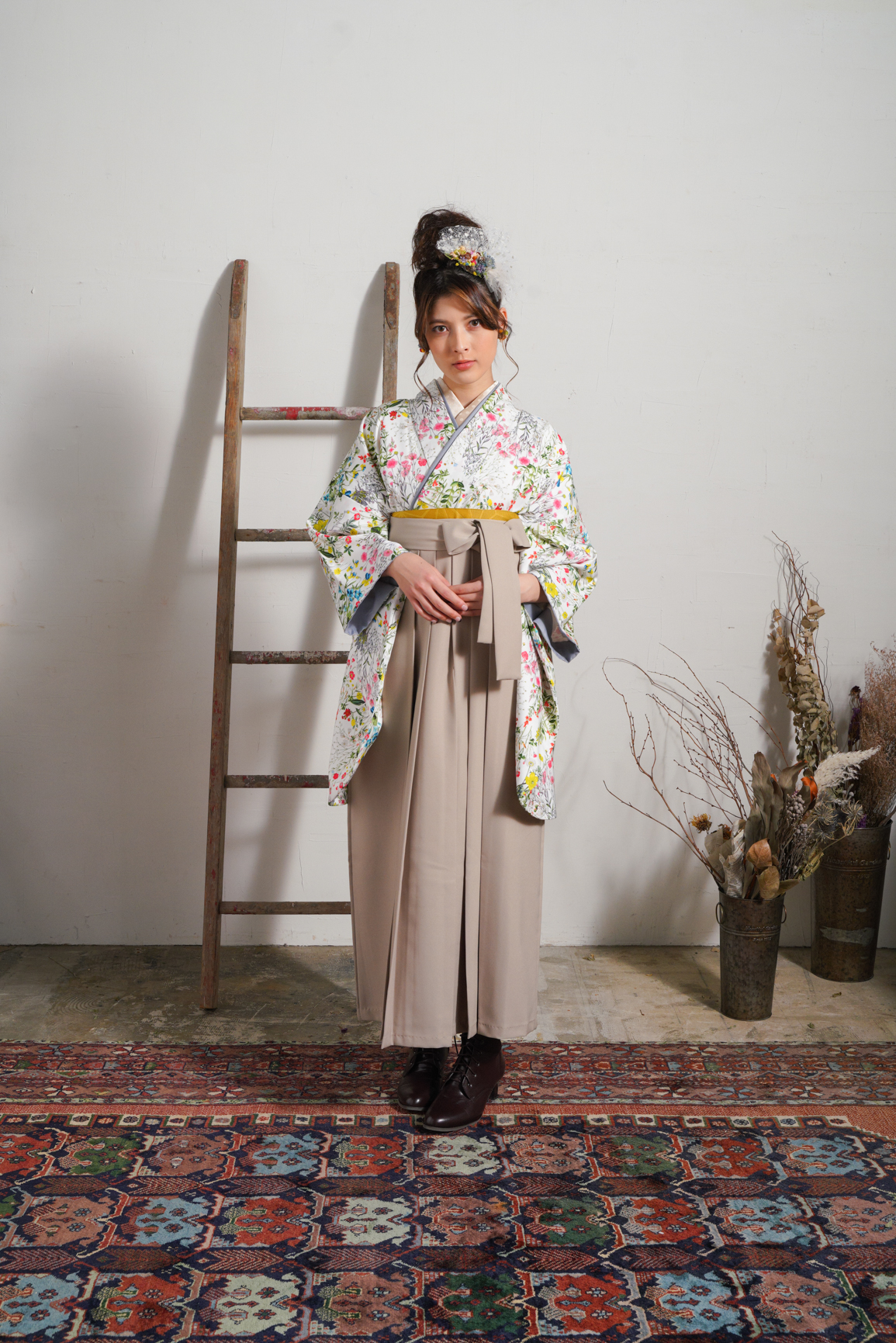 ラフィネモカ（Raffine Mocha）ブランドの、白地にカラフルな総小花柄の二尺袖と、ベージュ色の袴の女性用卒業式袴を着用した全身写真