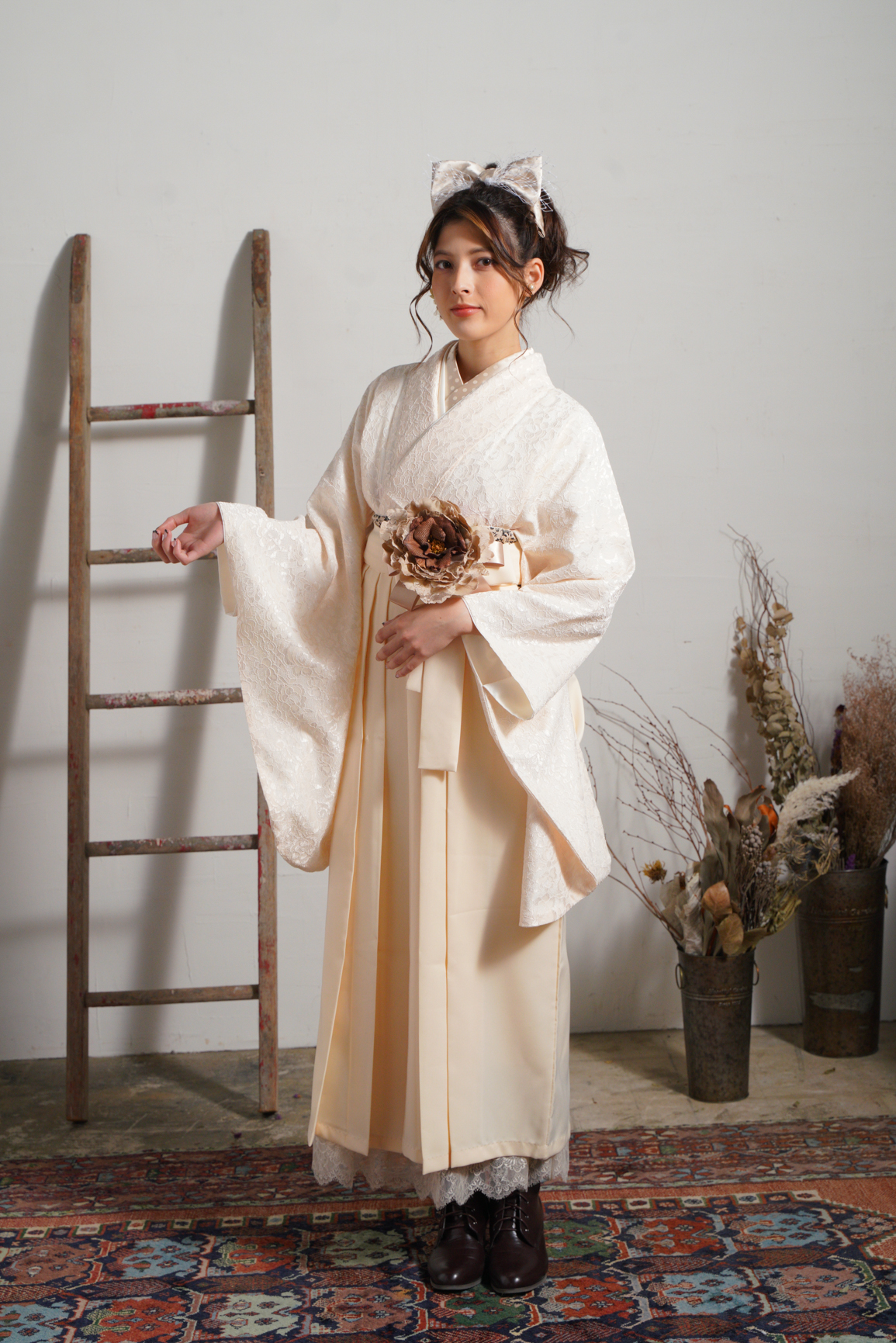 ラフィネモカ（Raffine Mocha）ブランドの、白の総レースの二尺袖と、クリーム色の袴の女性用卒業式袴を着用した全身写真