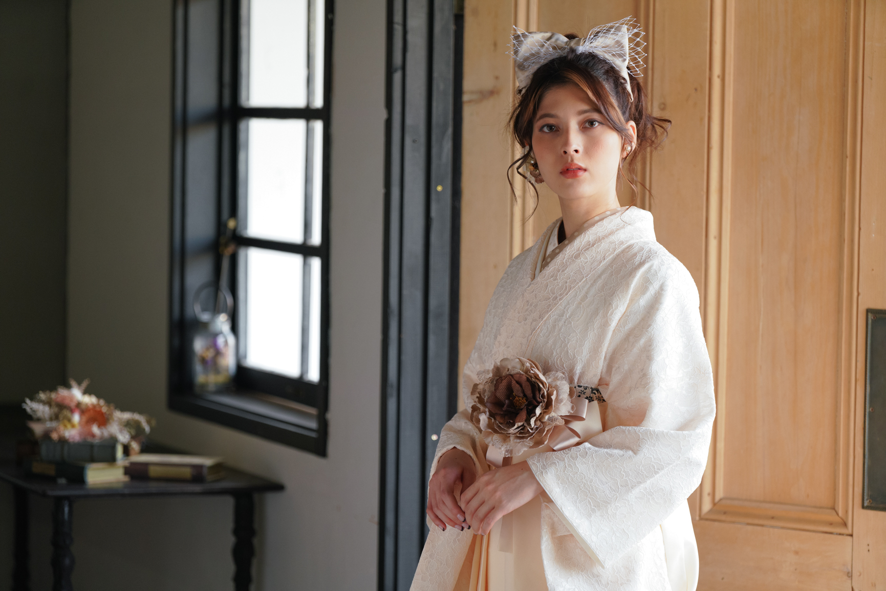 ラフィネモカ（Raffine Mocha）ブランドの、白の総レースの二尺袖と、クリーム色の袴の女性用卒業式袴を着用したバストアップ写真