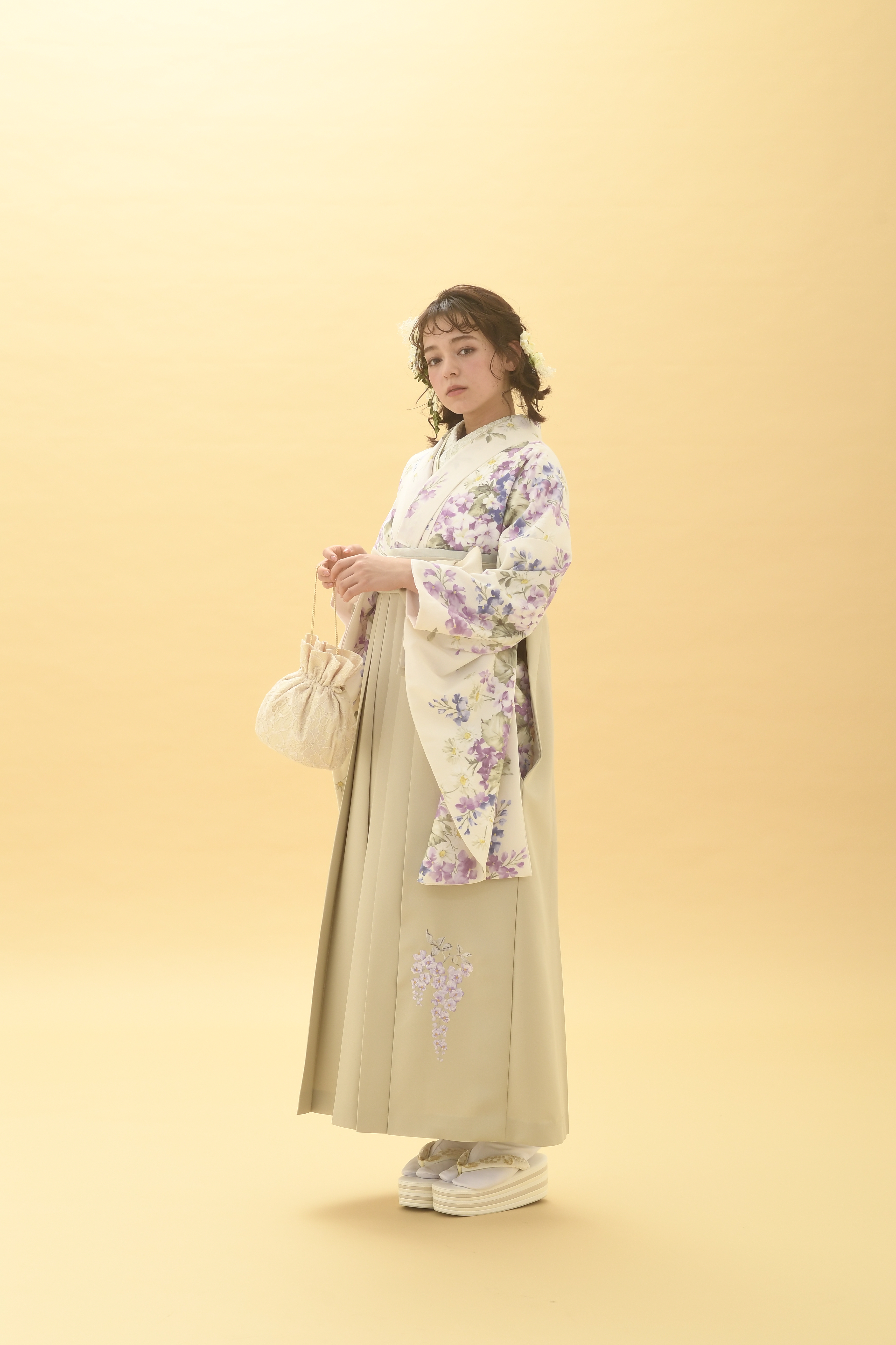 シュガーKブランドの、クリーム地に小花柄の二尺袖と、クリーム色の袴の女性用卒業式袴を着用した全身写真