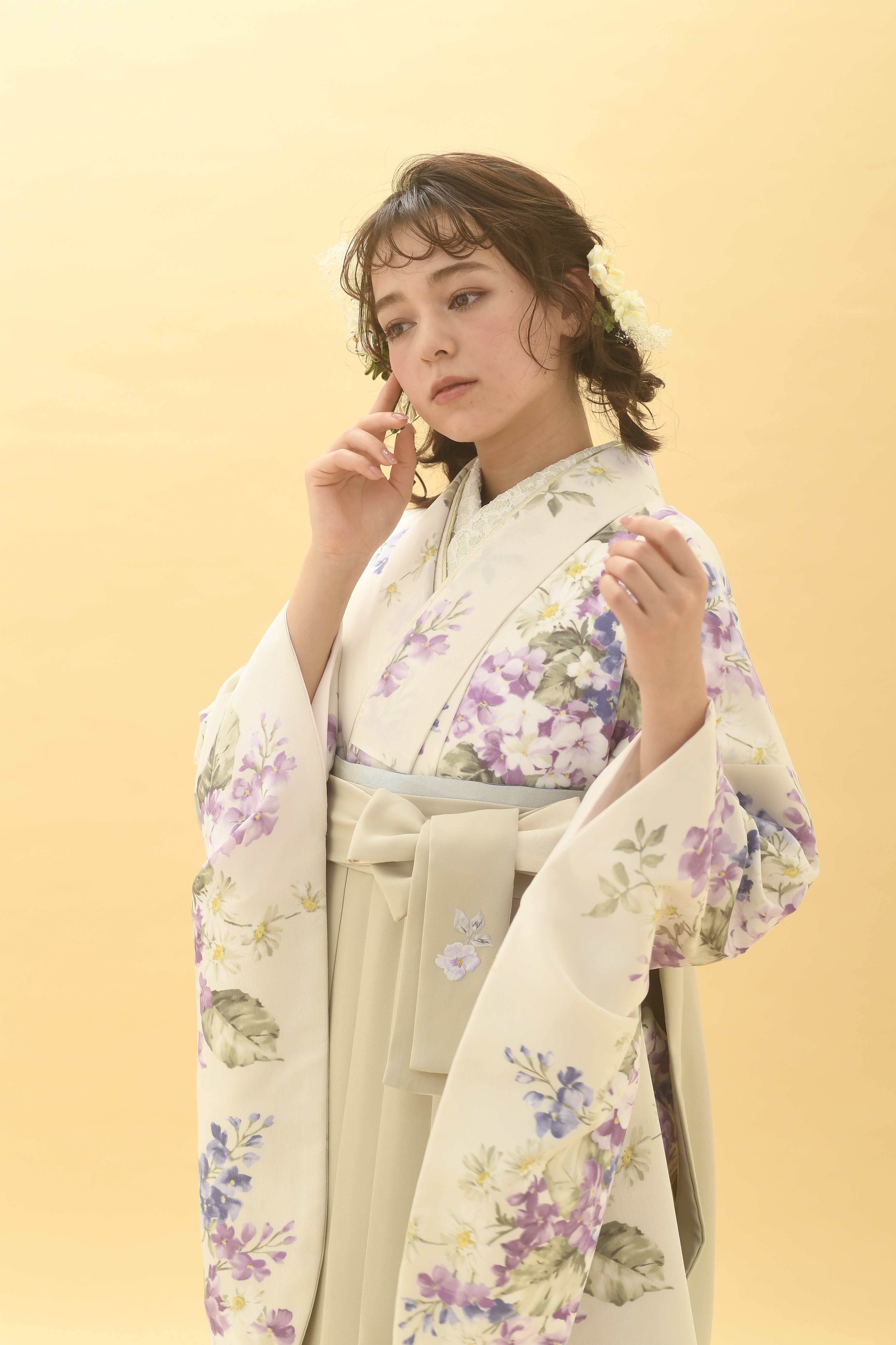 シュガーKブランドの、クリーム地に小花柄の二尺袖と、クリーム色の袴の女性用卒業式袴を着用したアップ写真