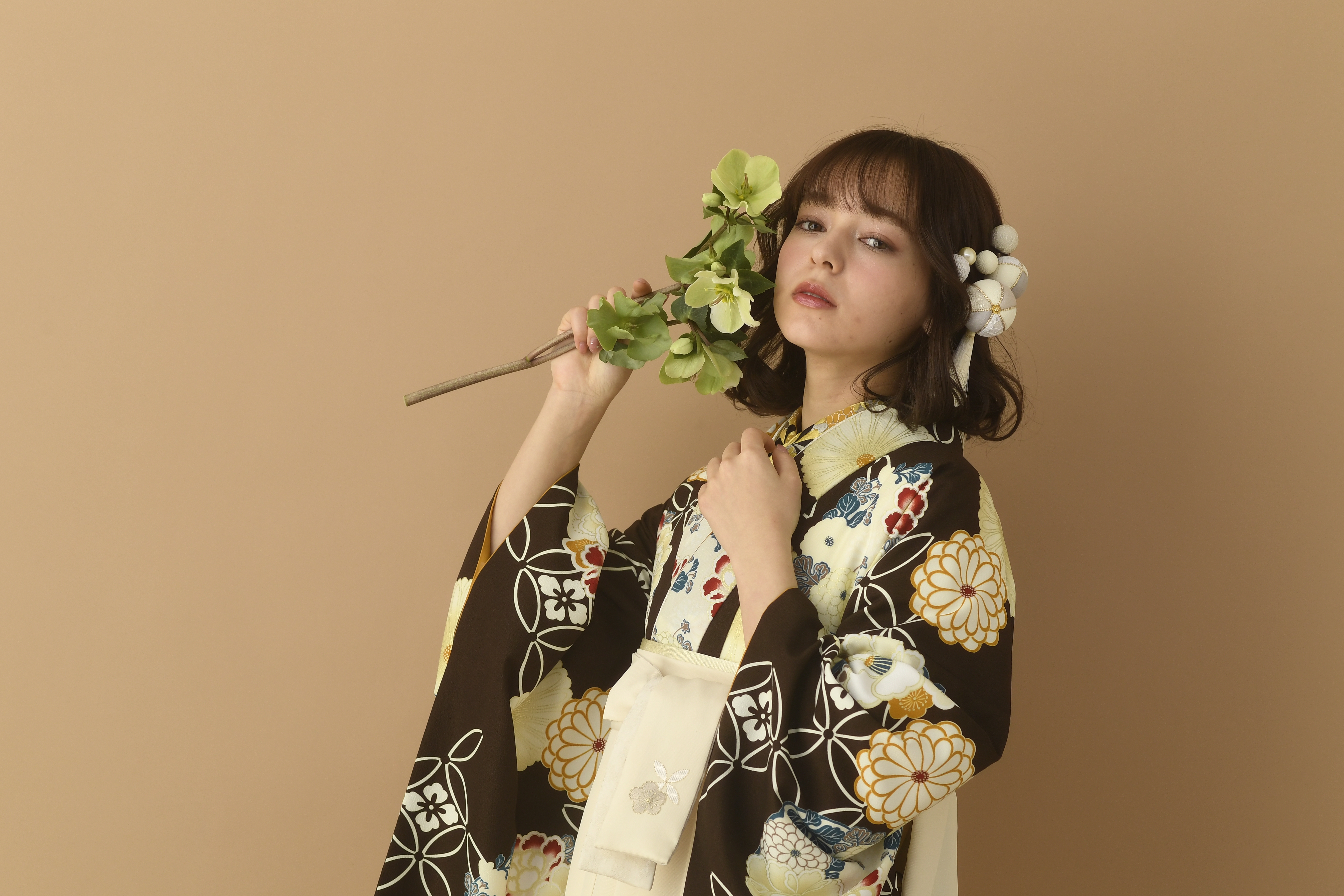 山本寛斎（ヤマモトカンサイ）ブランドの、黒地に白の花柄の二尺袖と、白の袴の女性用卒業式袴を着用したアップ写真