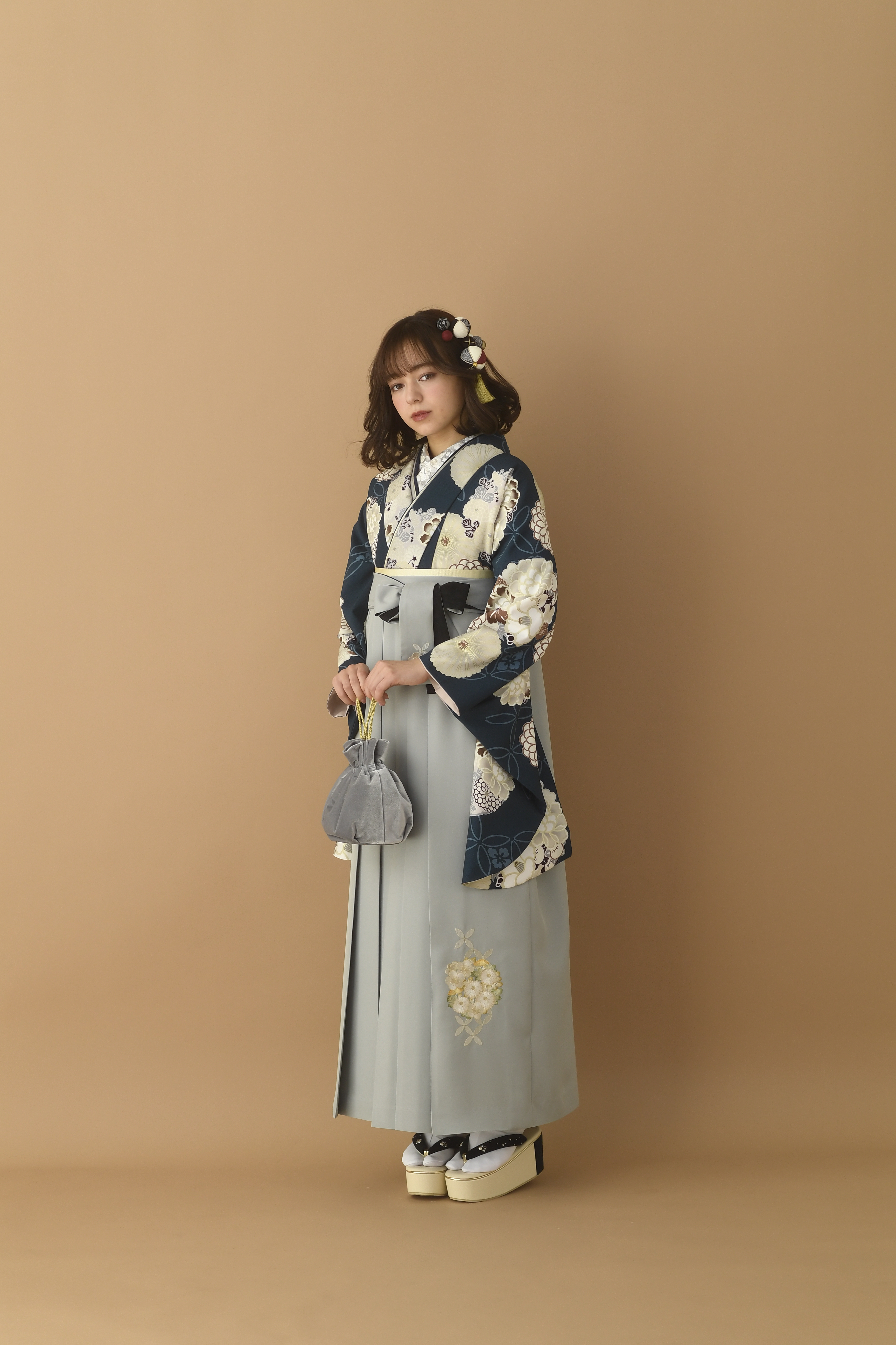 山本寛斎（ヤマモトカンサイ）ブランドの、紺地に白の花柄の二尺袖と、グレーの袴の女性用卒業式袴を着用した全身写真