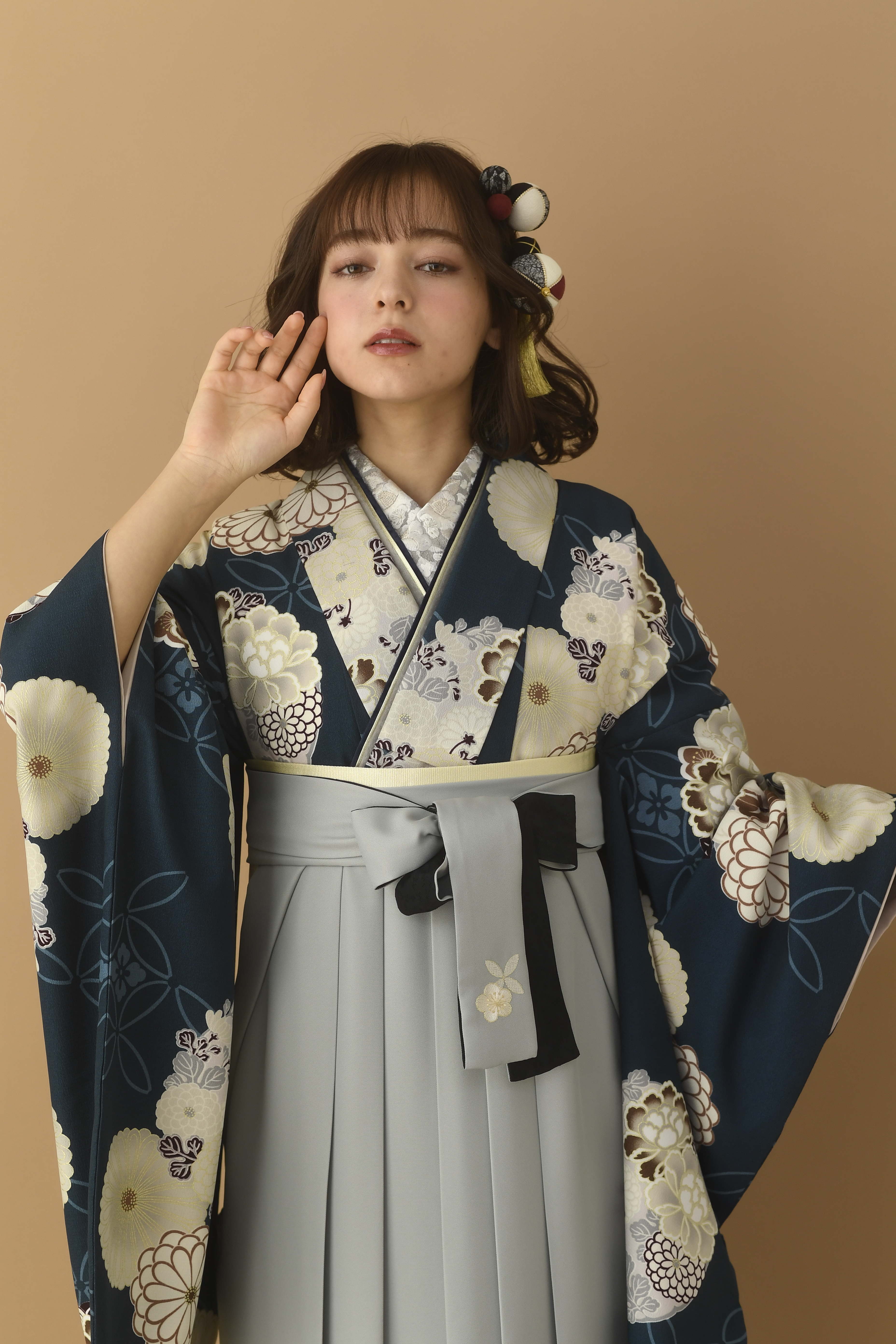 山本寛斎（ヤマモトカンサイ）ブランドの、紺地に白の花柄の二尺袖と、グレーの袴の女性用卒業式袴を着用したアップ写真