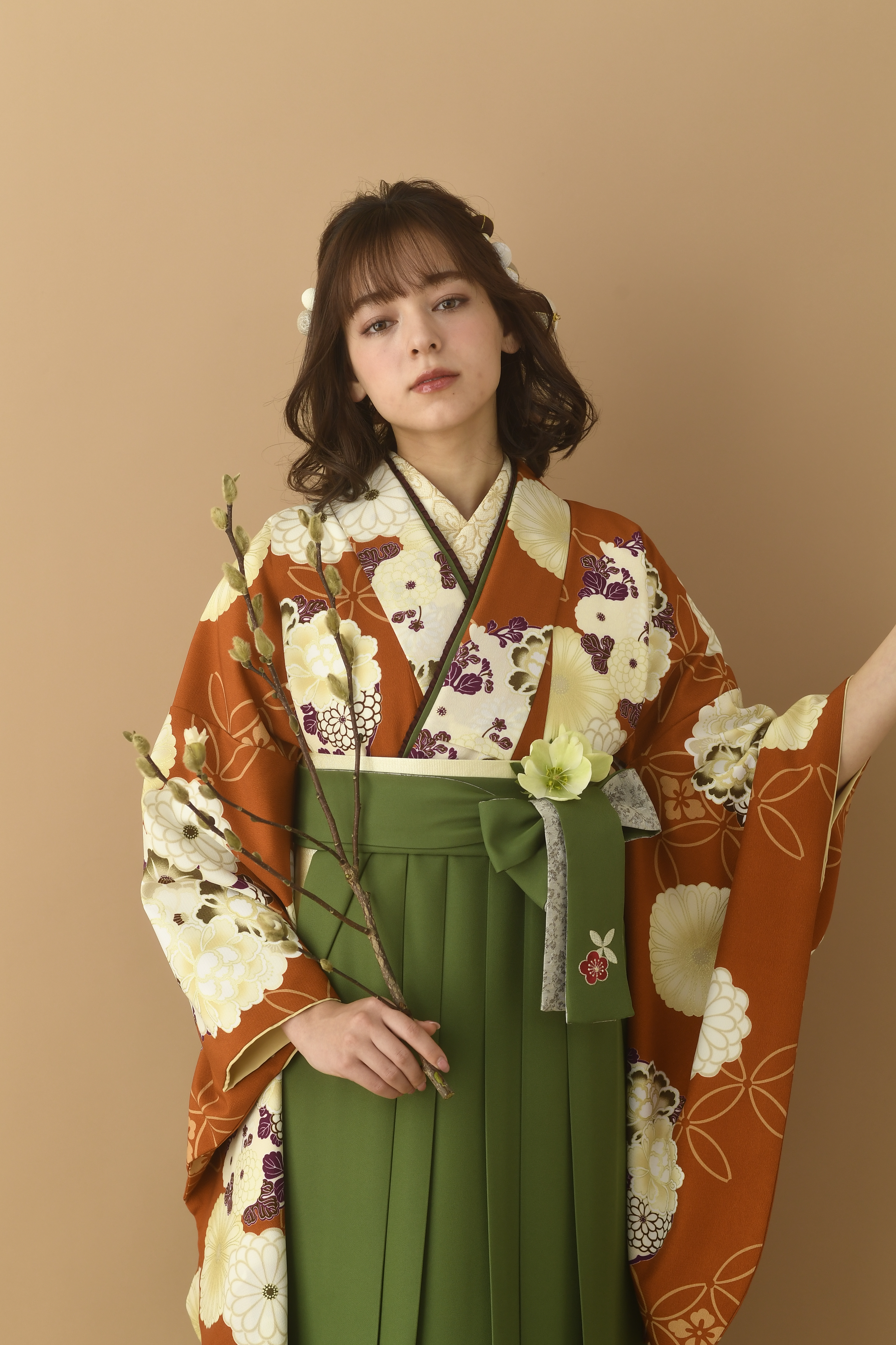 山本寛斎（ヤマモトカンサイ）ブランドの、エンジ地に白の花柄の二尺袖と、緑の袴の女性用卒業式袴を着用したアップ写真
