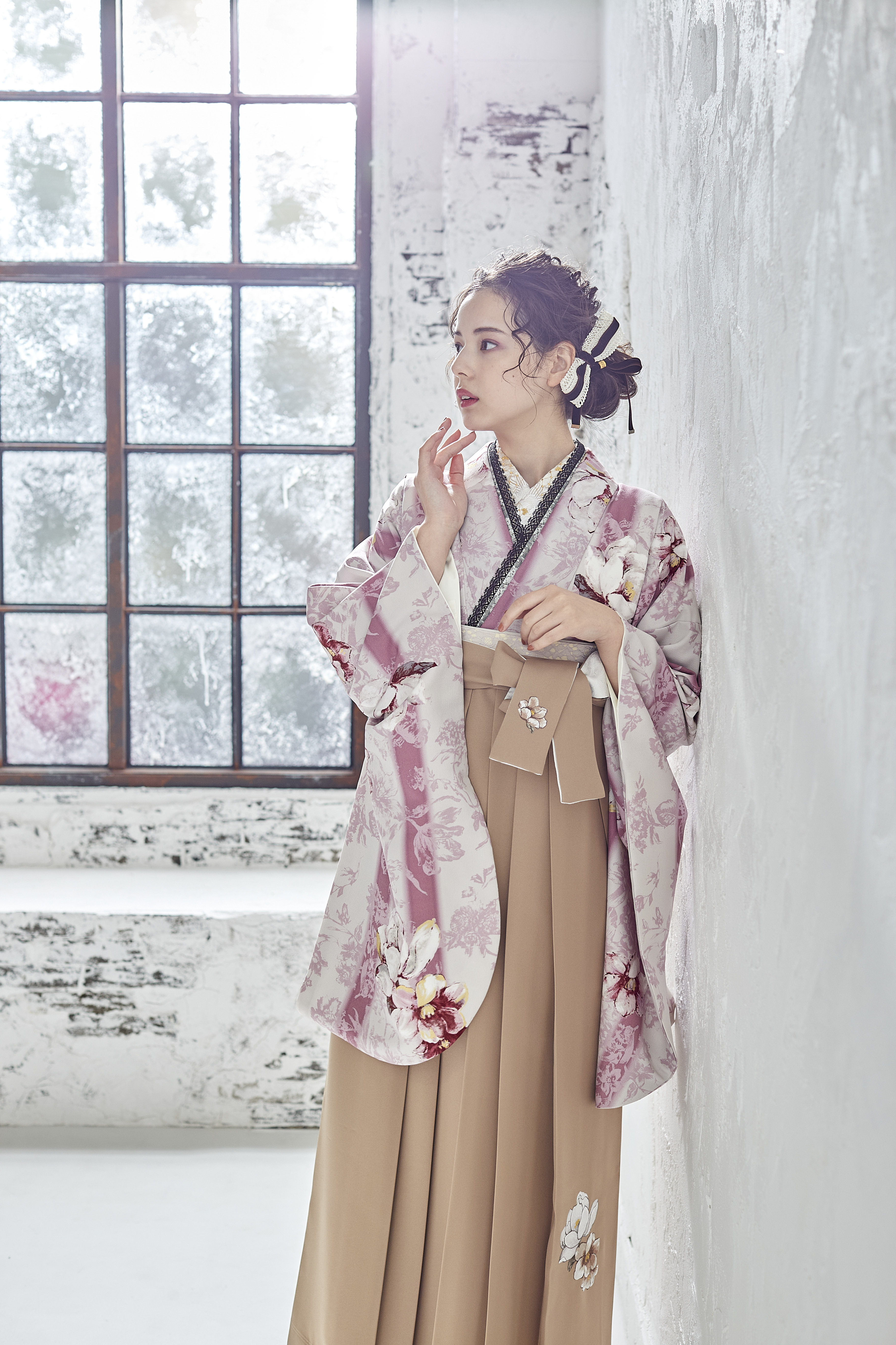 シュガーKブランドの、白地にピンクの花柄の二尺袖と、ベージュの袴の女性用卒業式袴を着用したアップ写真