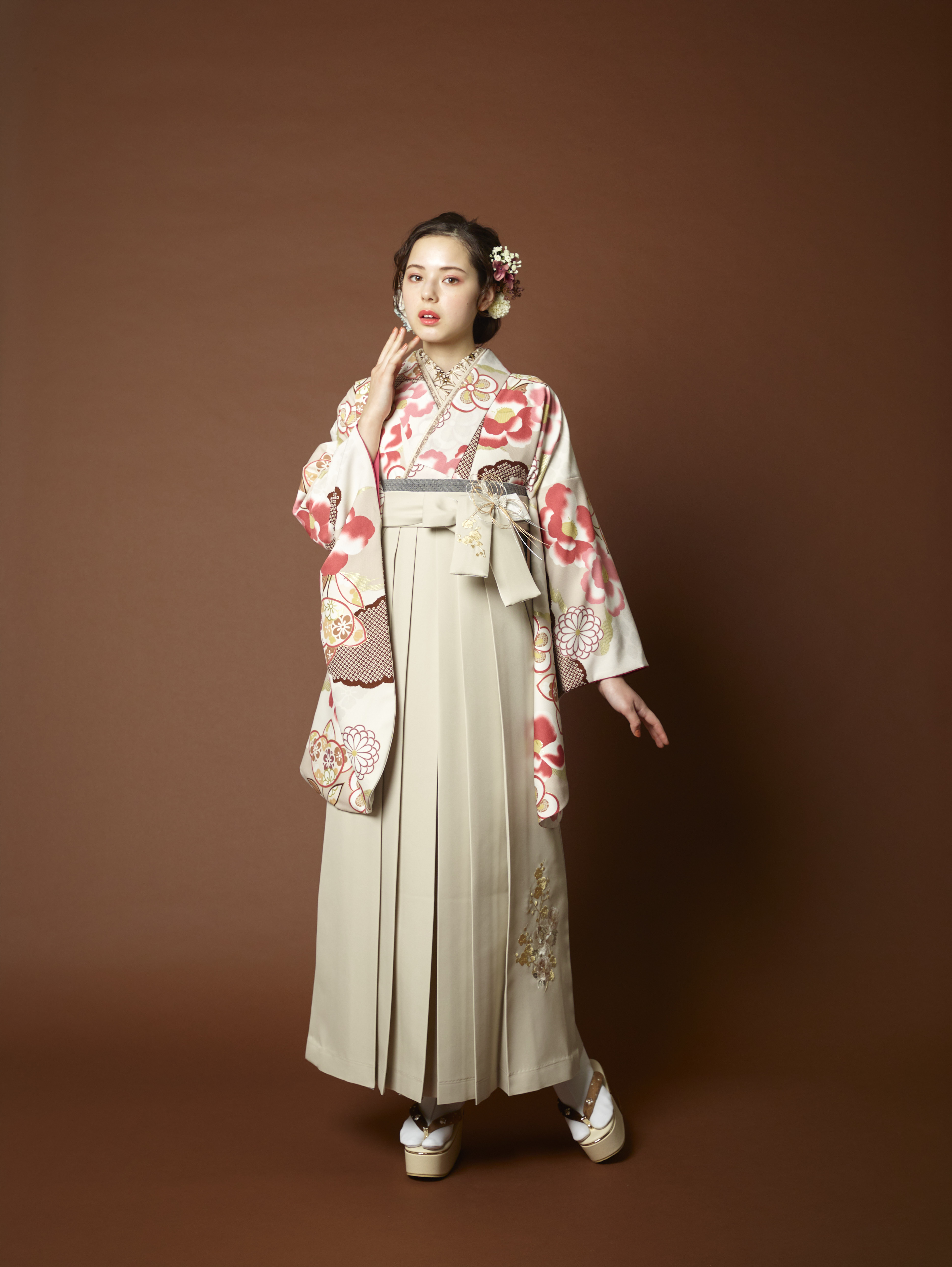 山本寛斎（ヤマモトカンサイ）ブランドの、白地にピンクの花柄の二尺袖と、白色の袴の女性用卒業式袴を着用した全身写真