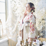 山本寛斎（ヤマモトカンサイ）ブランドの、白地にピンクの花柄の二尺袖と、白色の袴の女性用卒業式袴を着用したアップ写真