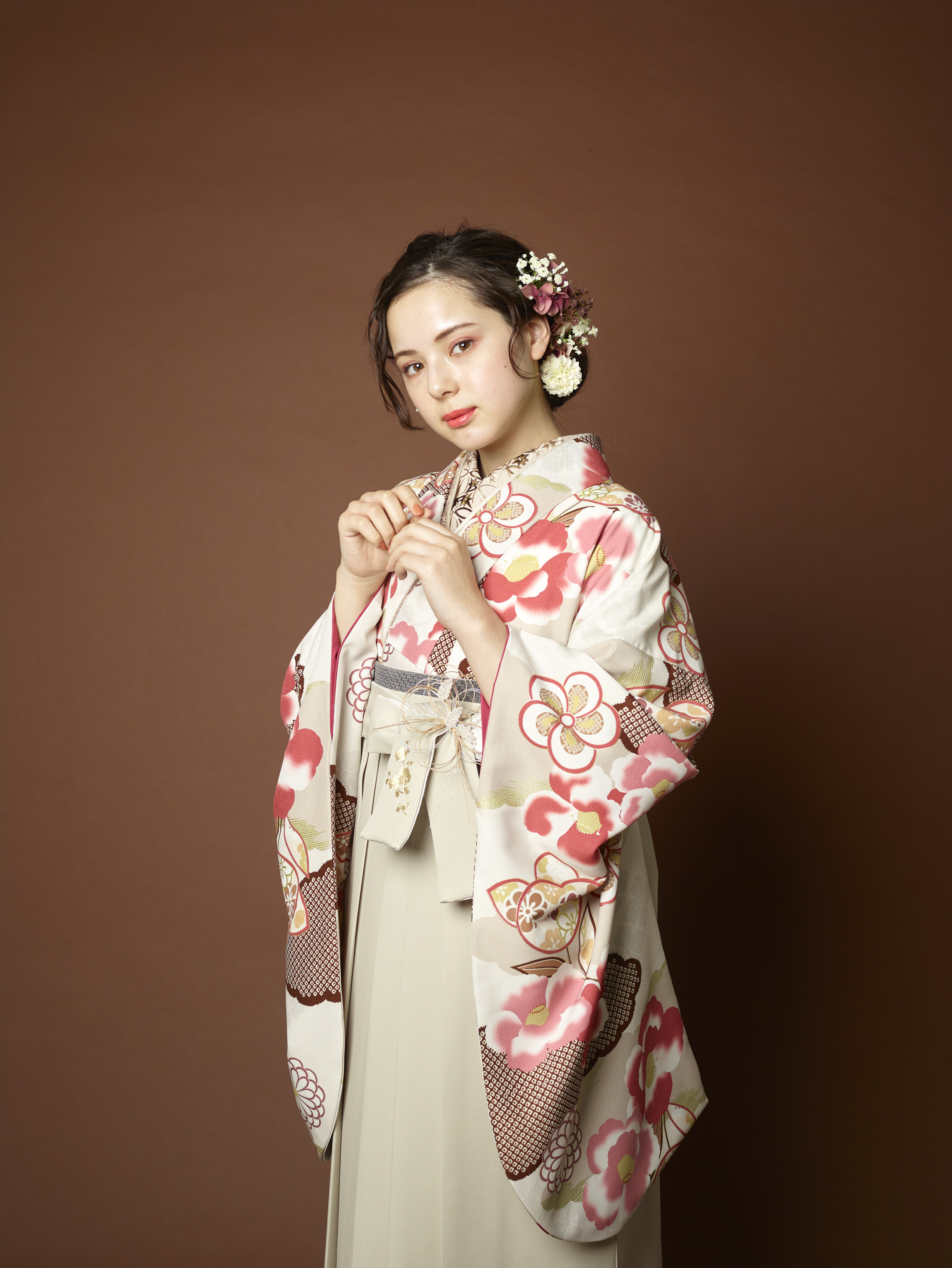 山本寛斎（ヤマモトカンサイ）ブランドの、白地にピンクの花柄の二尺袖と、白色の袴の女性用卒業式袴を着用したアップ写真2パターン目