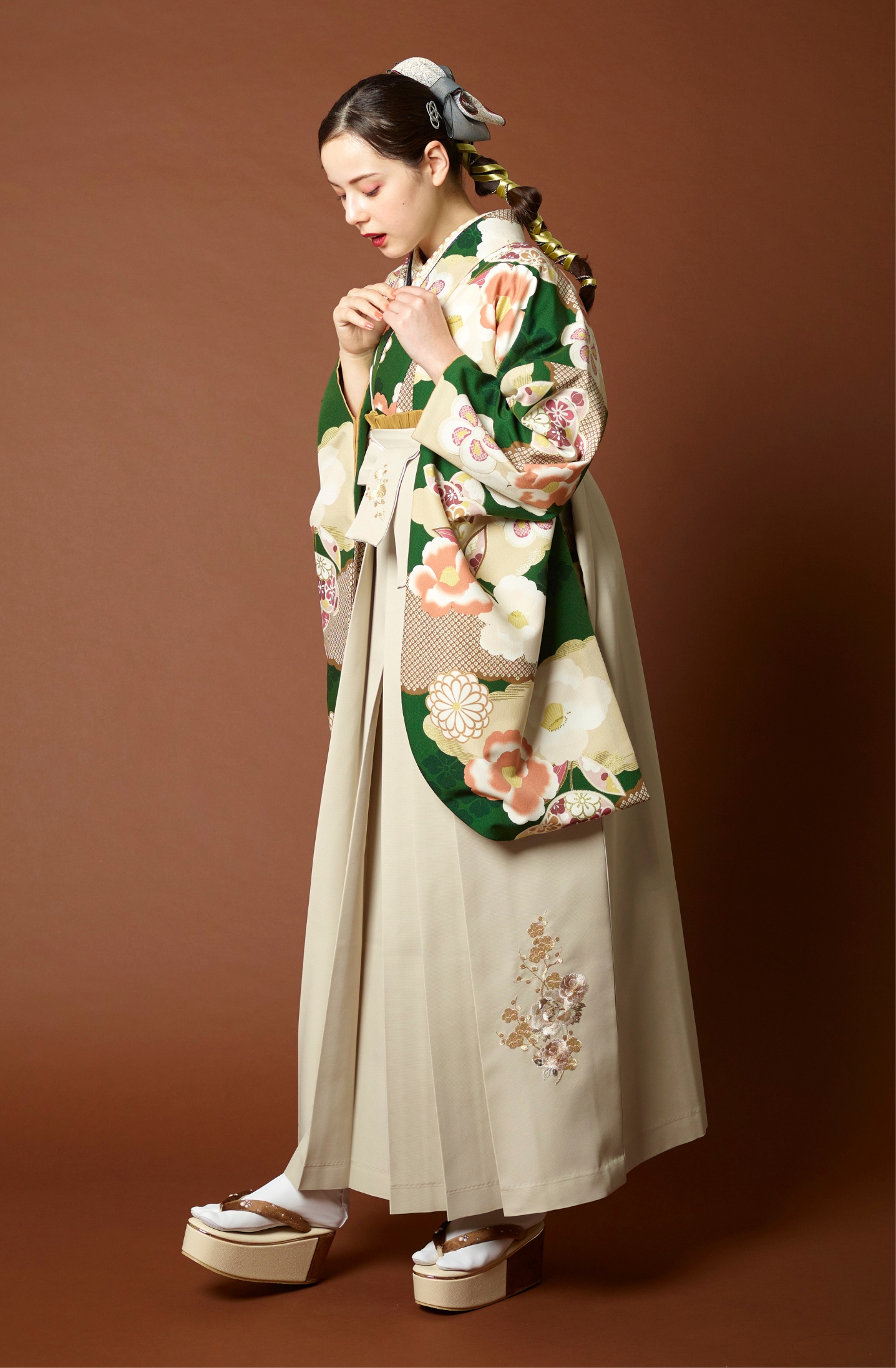 山本寛斎ブランドの、緑地に白の花柄の二尺袖と、白の袴の女性用卒業式袴を着用した全身写真