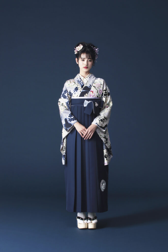 NATURAL BEAUTYブランドの、紺地に花柄の二尺袖と、紺の袴の女性用卒業式袴を着用した全身写真