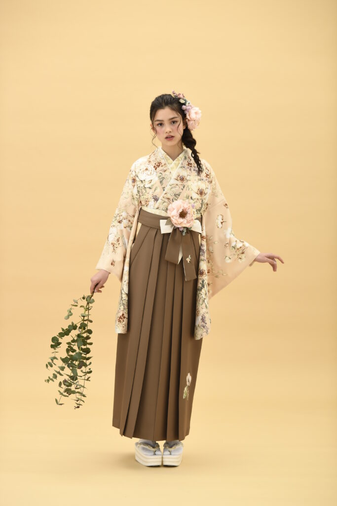 SUGAR KEIブランドの、ピンク地に花柄の二尺袖と、ブラウンの袴の女性用卒業式袴を着用した全身写真