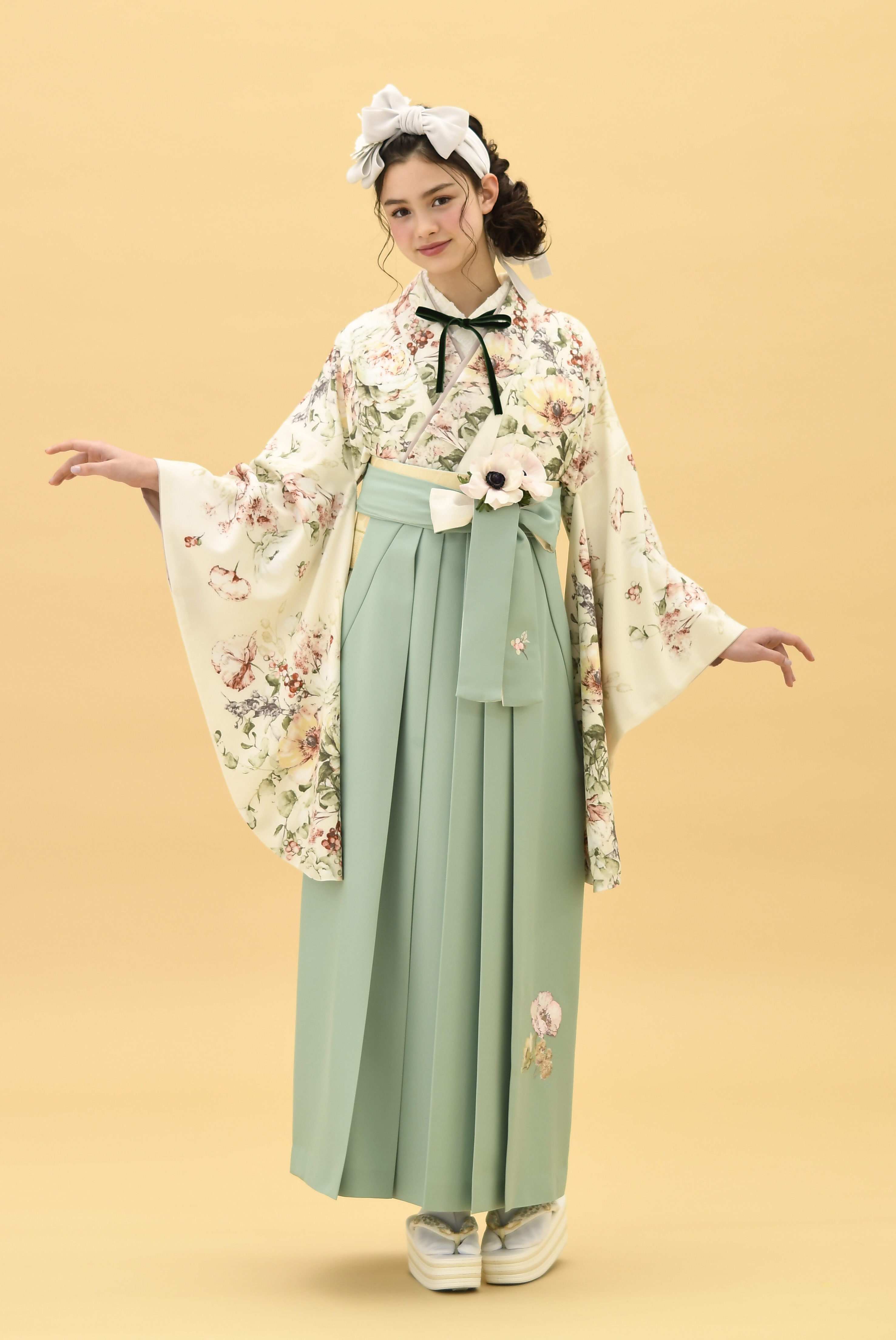 SUGAR KEIブランドの、クリーム地に淡いピンクの花柄の二尺袖と、ミントグリーンの袴の女性用卒業式袴を着用した全身写真
