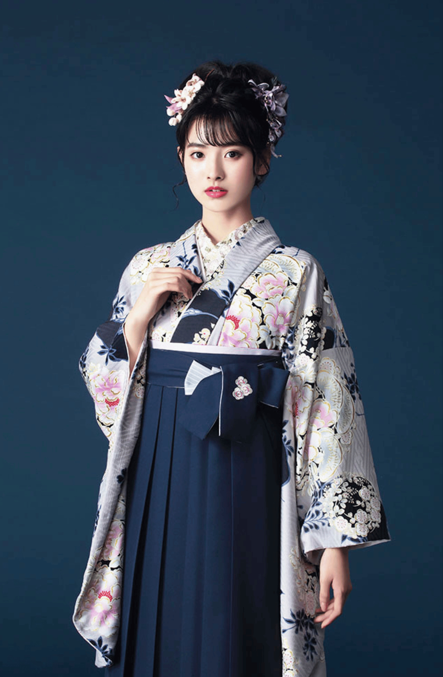 NATURAL BEAUTYブランドの、紺地に花柄の二尺袖と、紺の袴の女性用卒業式袴を着用したポートレート